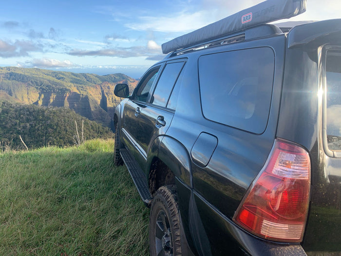 Black adventure SUV with awning at scenic cliff overlook. Ideal for a rugged RV rental experience.