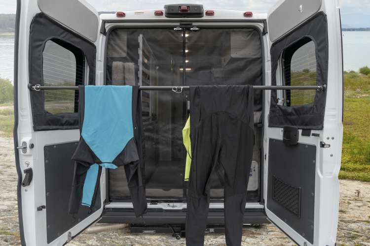 RV rental's rear doors open, featuring a drying bar for activewear. Ideal for adventurers to dry gear outdoors.