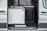 Modern rv rental camper van interior featuring a sleek kitchen counter, sink faucet, and refrigerator.