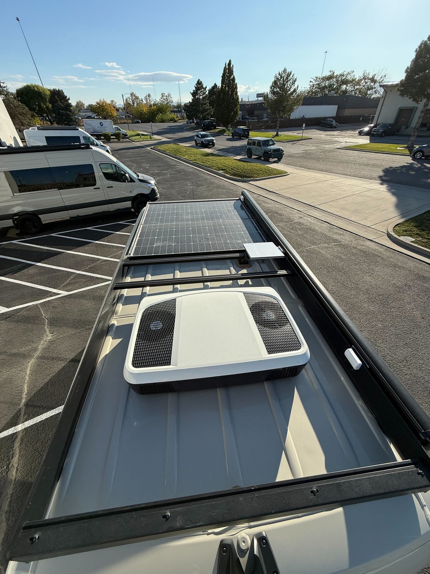 High-angle view of an rv rental van's roof: solar panels, rooftop AC, and Starlink dish visible. Ready for remote adventures.