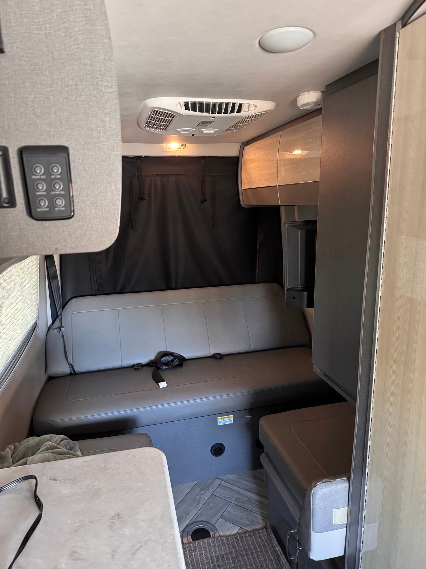 Inside this RV rental: a modern living space with comfy bench seating, ceiling AC, and storage. Perfect for road trips. — photo 7