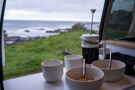 RV rental breakfast setup: fresh coffee, cereal, and a breathtaking ocean view from inside the camper.