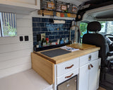 This compact RV rental features a functional camper van kitchen with blue tile, wood counters, smart storage, and Hedgehog decor.