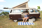 Couple relaxing in an **rv rental** camper van with pop-top open, enjoying an ocean view. Perfect for **travel** adventures.