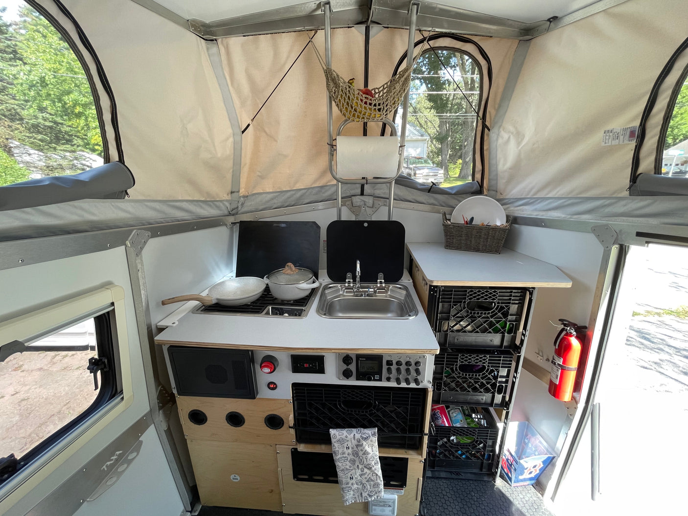 Step into this RV rental's interior: a compact kitchenette, crate storage, and pop-up canvas walls create a cozy space.