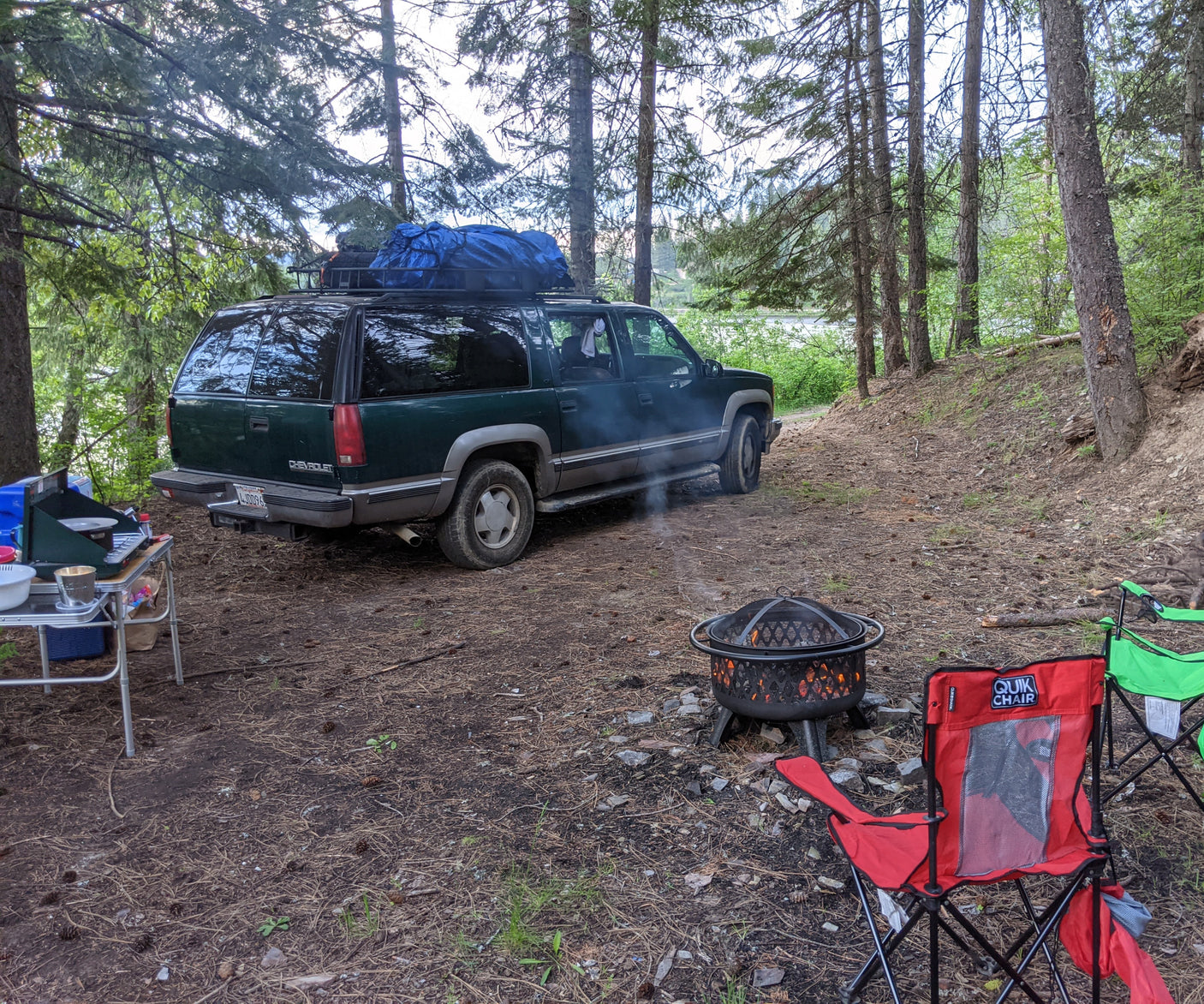 Campsite fun with an RV rental alternative: a Chevy Suburban, complete with a cozy fire pit, cooking setup, and chairs.