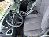 GMC car interior for your rv rental journey: black steering wheel, gauges, center console, patterned fabric seats with red stitching.