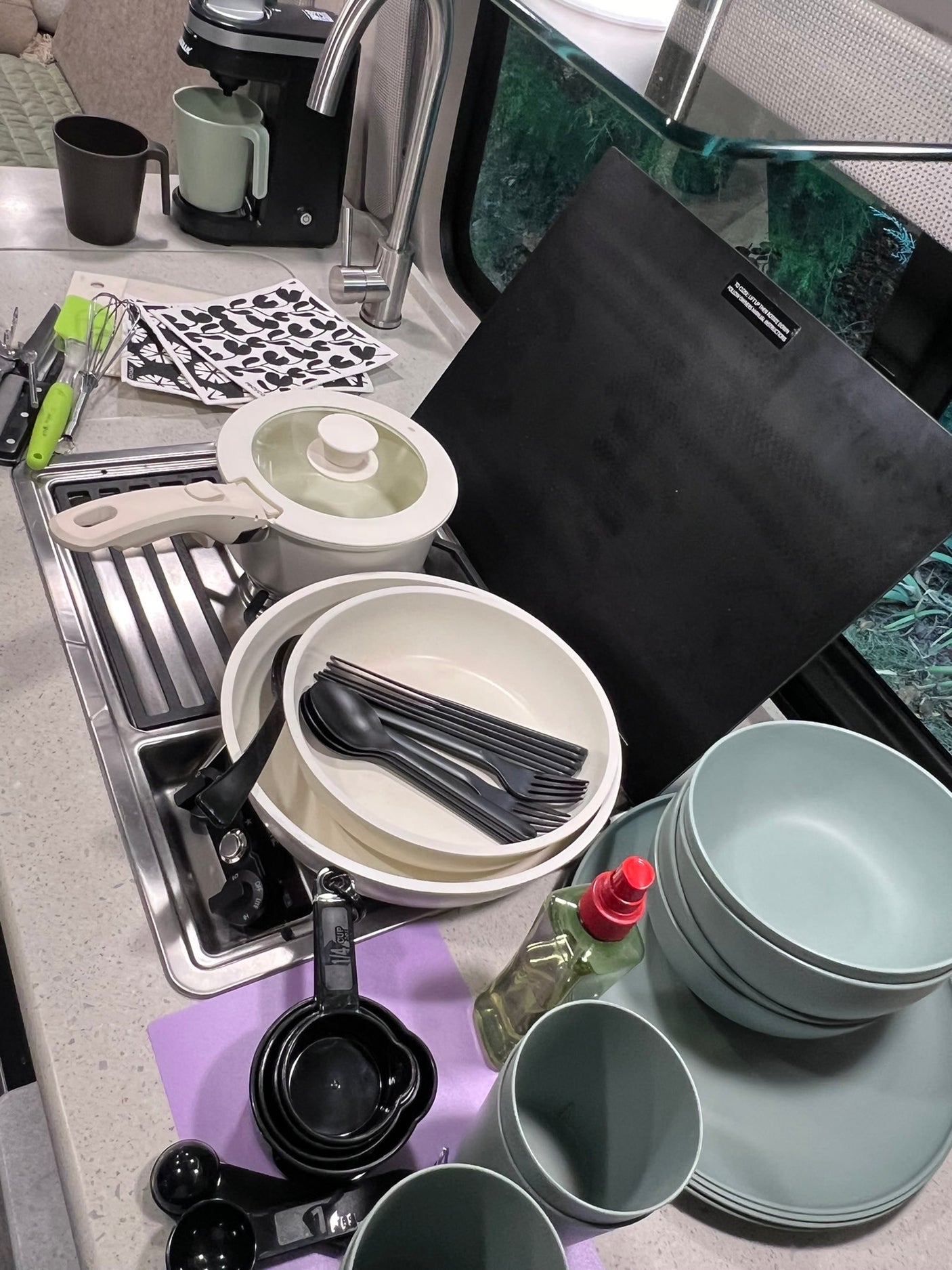 RV rental kitchen supplies: compact pots, plates, cutlery, coffee maker, and measuring tools for camping trips.