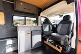 Interior of an RV rental camper van, showing a compact kitchen, seating, and scenic window view. Ideal for van life.