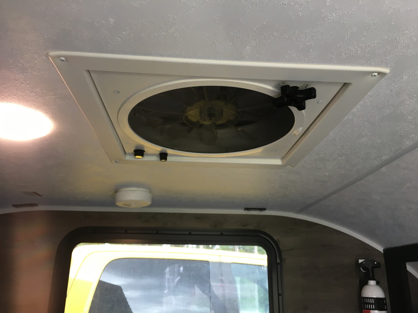 Inside an RV rental: a ceiling fan with lights, smoke detector, and fire extinguisher are visible, ensuring comfort and safety. — photo 8