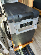 A grey and black portable electric cooler displays 79°F, nestled in an RV rental for convenient travel and camping.