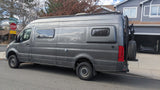 This custom gray Mercedes Sprinter camper van is perfect for rv rental trips. It has a roof rack, rear gear carrier, and distinctive windows.