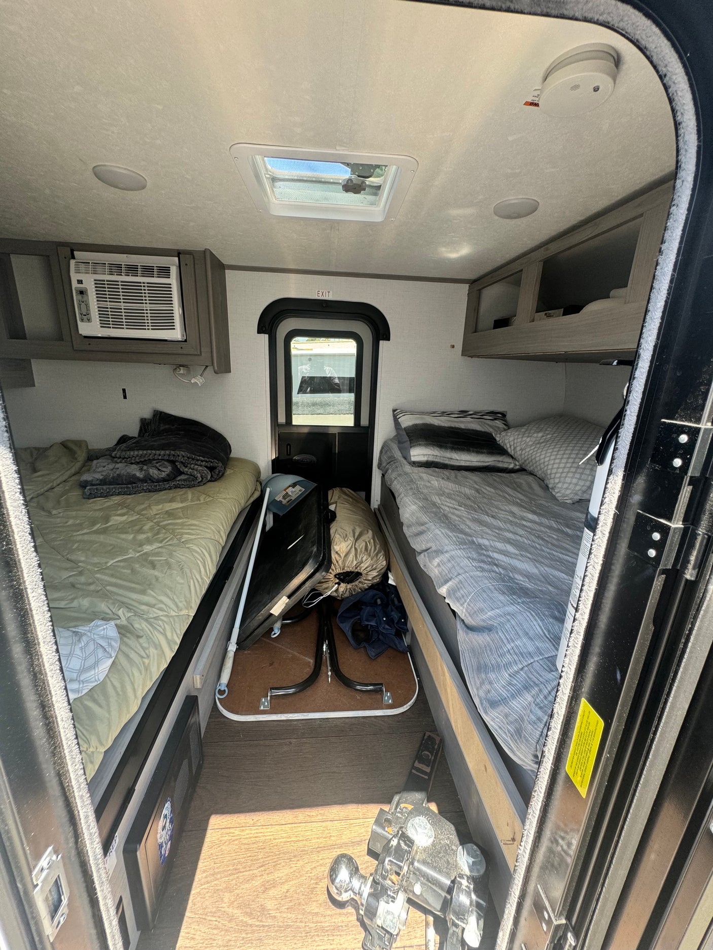 Cozy RV rental interior featuring twin beds, AC, skylight, and overhead storage, designed for compact travel.