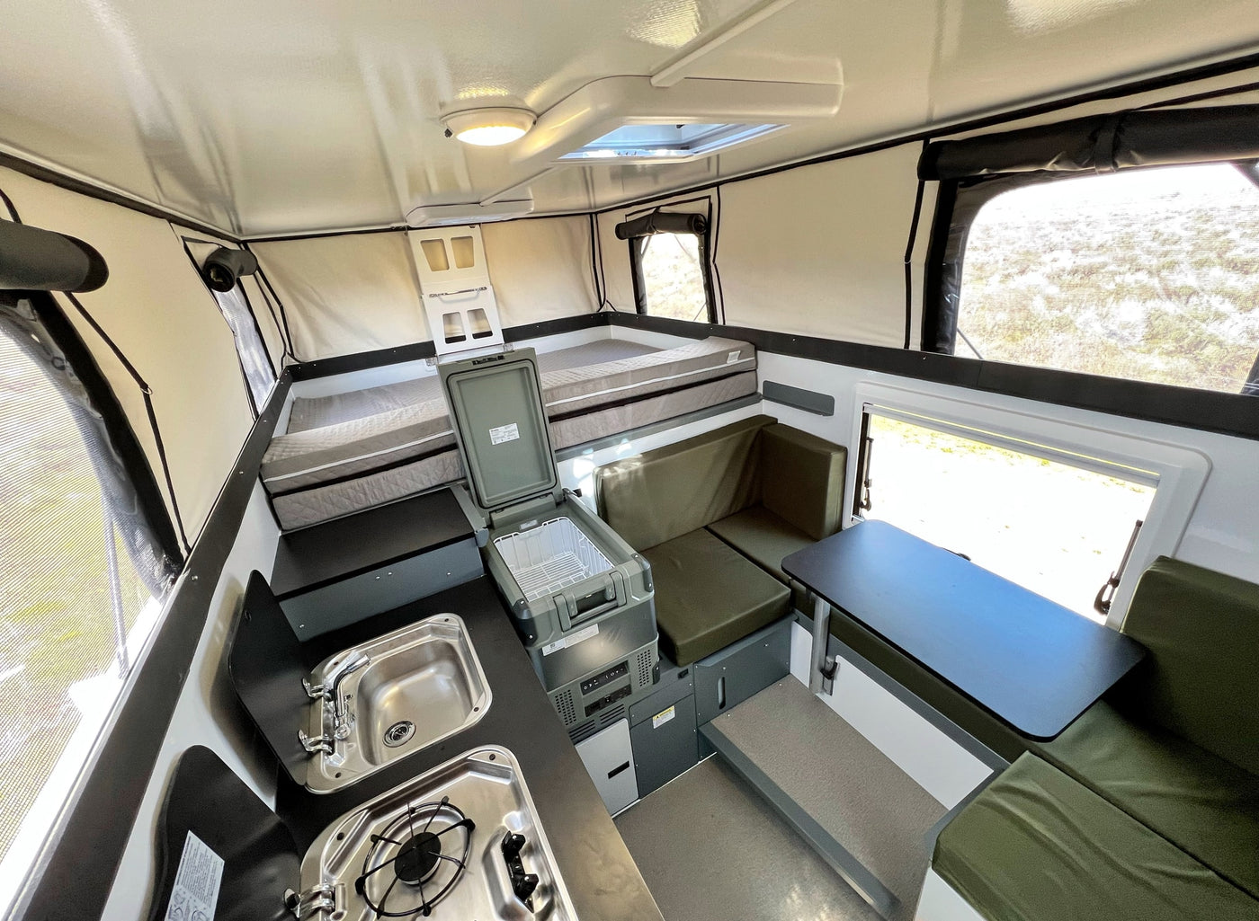 RV rental interior: comfy bed, compact kitchen with sink/stove, and dining area. Ready for adventure! — photo 11