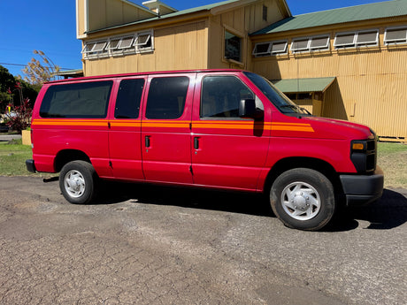 Vibrant red van with orange stripes, a spacious RV rental option, parked on asphalt near a large building.