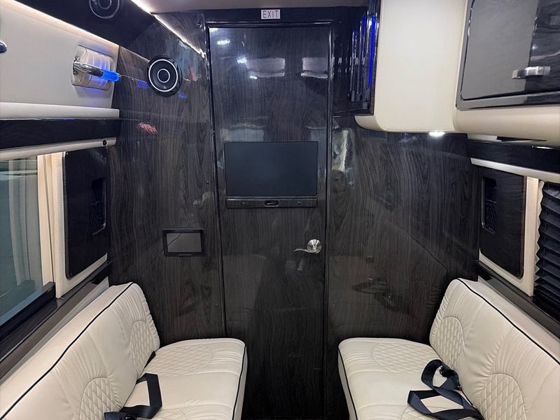  view towards the dashboard and front windshield into a parking lot.|Spacious RV rental interior featuring facing beige leather benches with quilting — photo 4