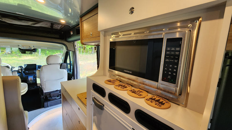 Modern **RV rental** kitchen with a Contoure microwave, counter, "Up North" coasters, and view of the front cabin. — photo 18