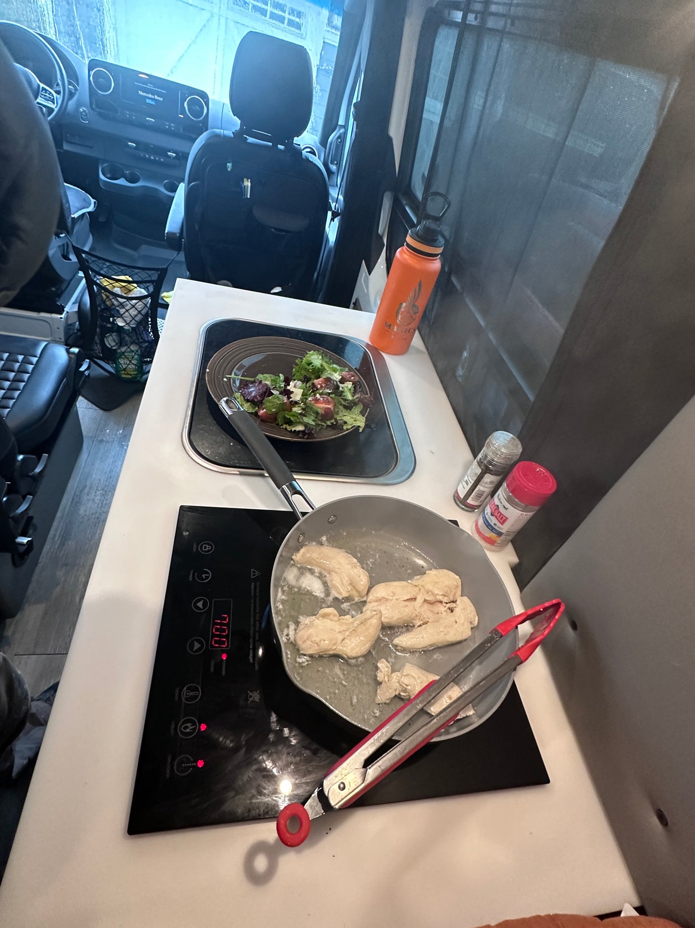 Cooking fresh chicken and salad inside a Mercedes-Benz rv rental. A glimpse of mobile kitchen life.