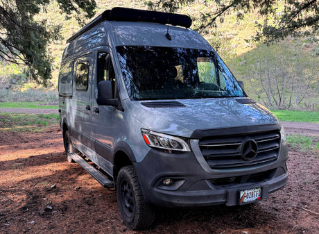 Gray Mercedes Sprinter van rv rental, an off-road camper, ready for Idaho adventures, parked on a dirt path.