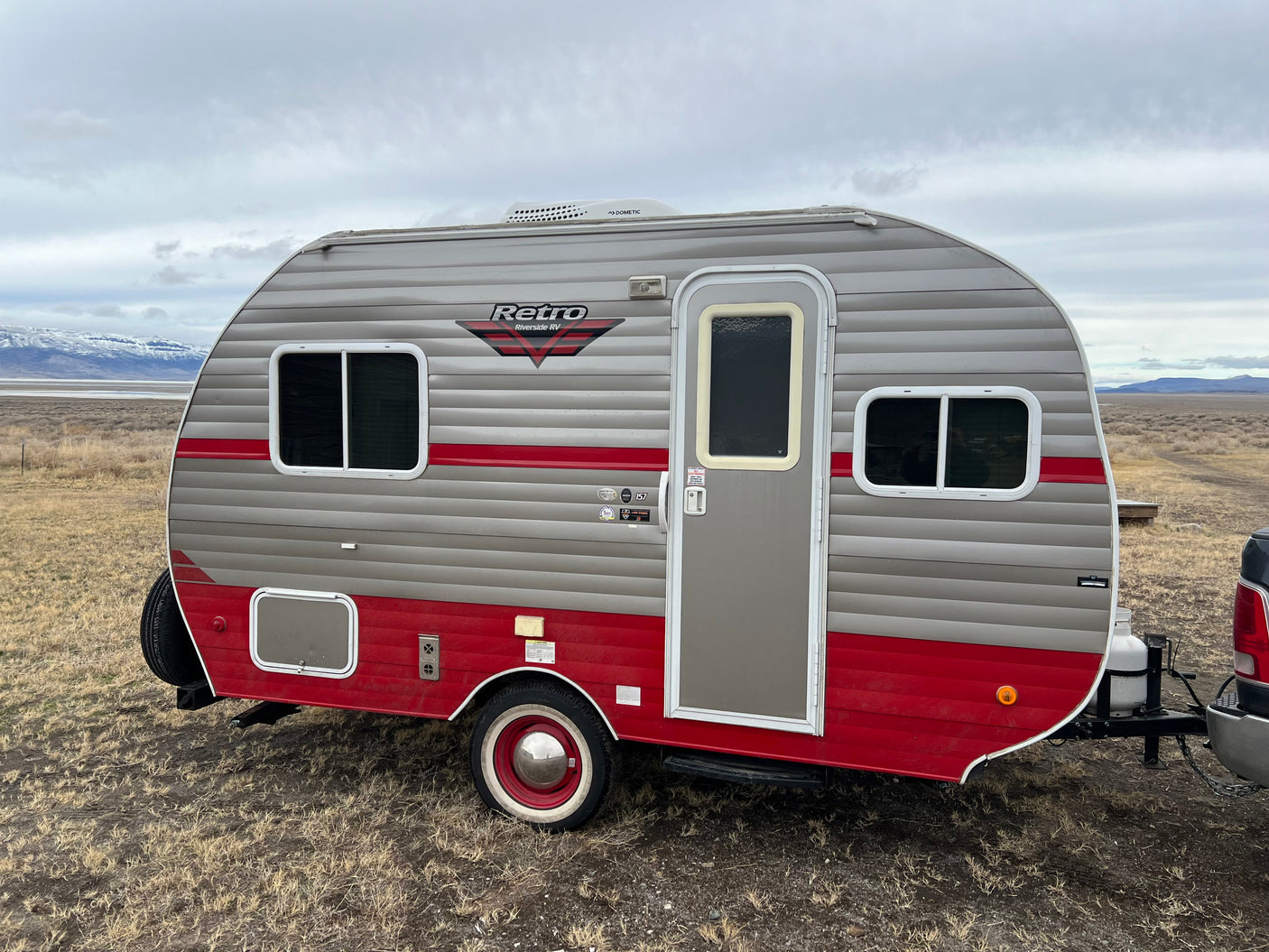 Retro Riverside RV travel trailer, perfect for an RV rental getaway. Parked in a vast, dry landscape.