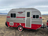 Retro Riverside RV travel trailer, perfect for an RV rental getaway. Parked in a vast, dry landscape.