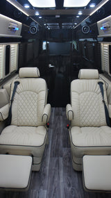 Luxury RV rental interior: comfortable, cream-quilted leather seats, footrests, dark wood-look flooring, and ambient lighting.