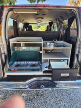 This RV rental camper van features a clever kitchen setup with a Coleman propane stove, sink, and Dometic cooler.