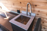 This RV rental features a compact kitchen with a stainless steel sink, gooseneck faucet, and natural wood paneling.