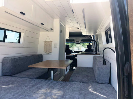  and panoramic outdoor views. Perfect for travel adventures.|This cozy RV rental's custom-built camper van interior features overhead storage