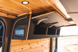 Inside a modern RV rental: wood-paneled ceiling, lift-up overhead storage, and integrated digital control panel.