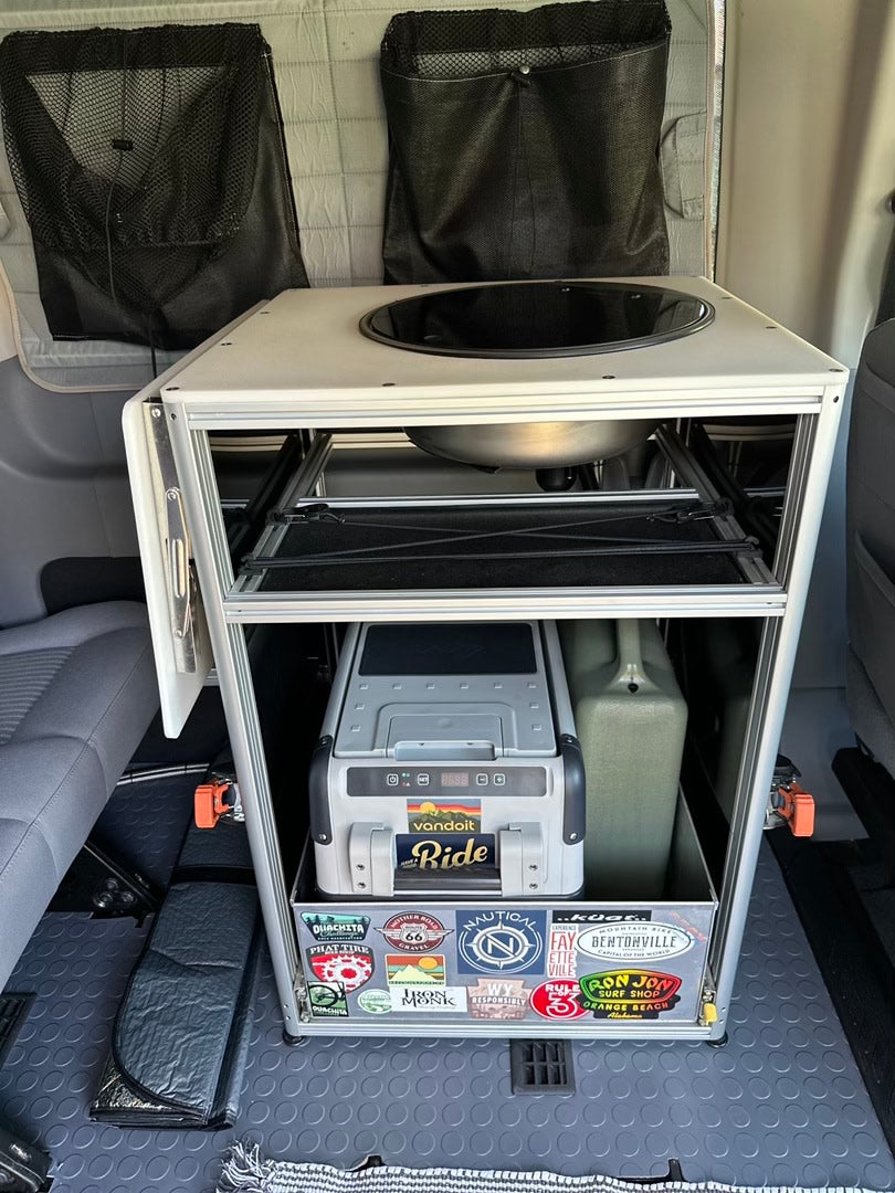 Compact RV rental kitchen module with a sink, pull-out fridge, and water tank for efficient campervan adventures.