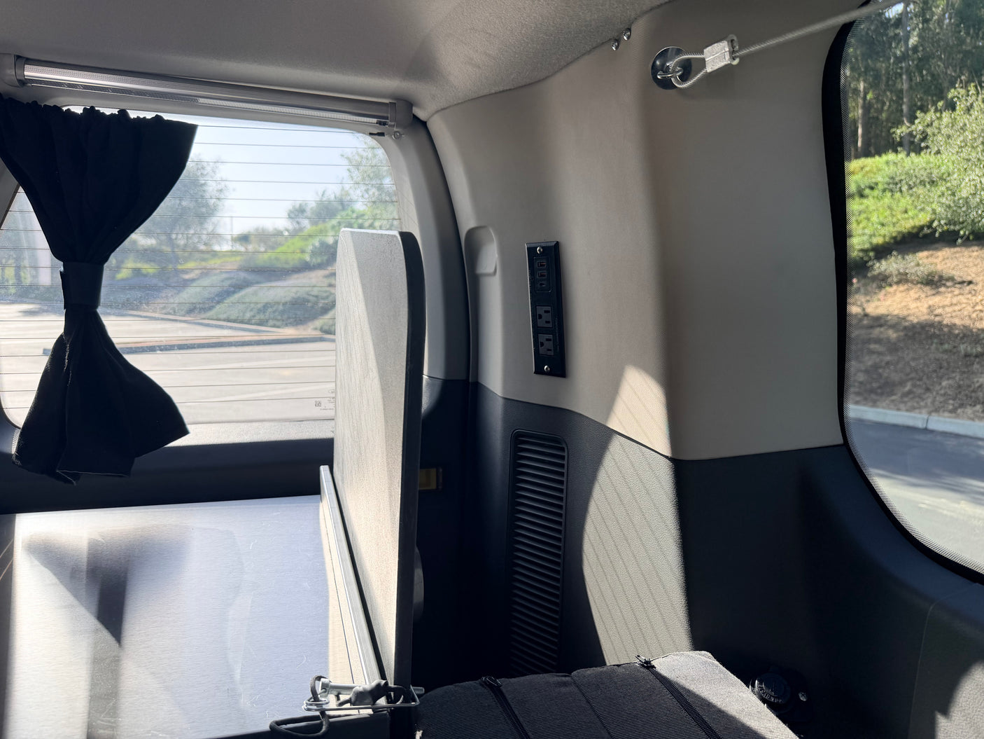 Inside a personalized rv rental: features a bed platform, essential power outlets, and a convenient privacy curtain.