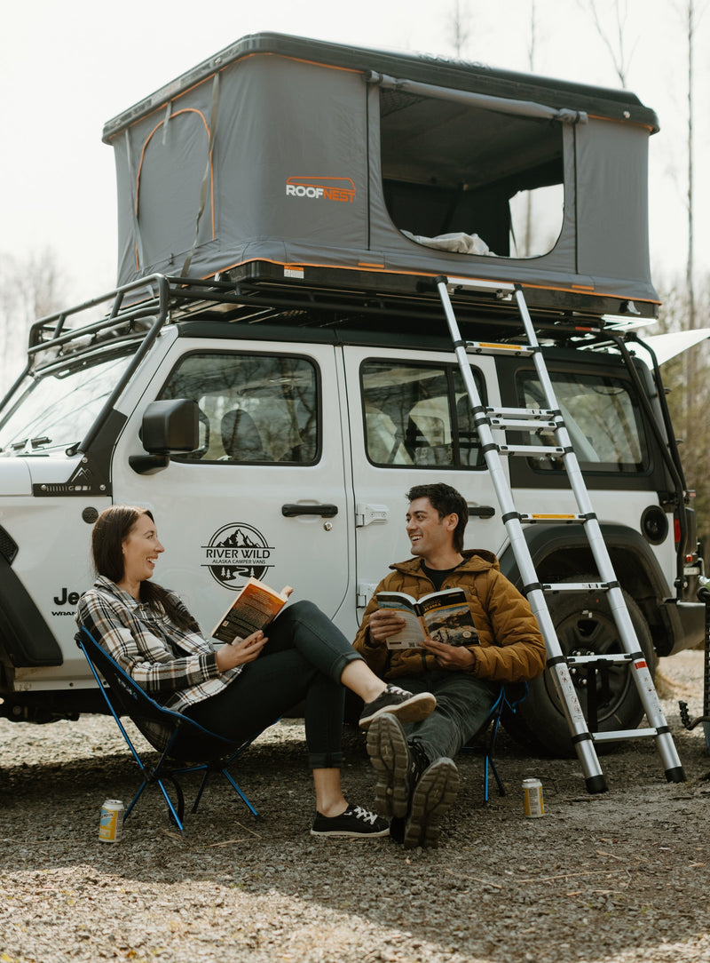 Two people relax by their RV rental, a Jeep Wrangler with a Roofnest rooftop tent, perfect for an Alaska camping adventure. — photo 2