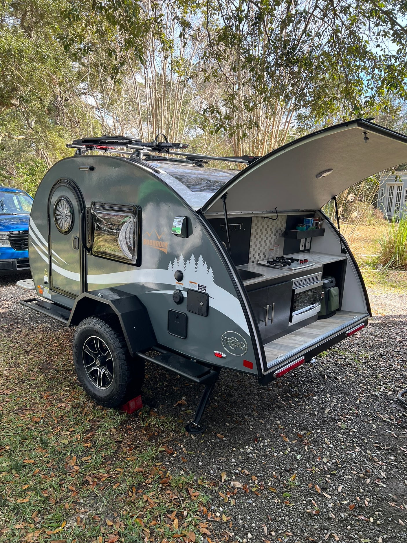 Grey Boondock teardrop camper RV rental with an open outdoor kitchen, ready for your next camping adventure.