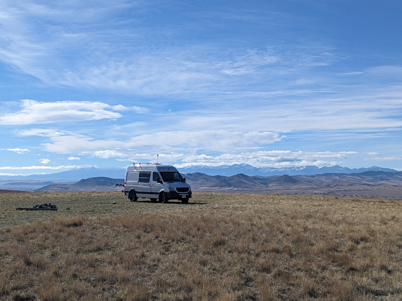 Freedom on wheels! An RV rental Sprinter van in a golden field, with snow-capped mountains under a blue sky.
