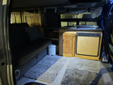 Step inside this cozy RV rental's living space: a compact kitchen, comfy bed, and soft floor mats for ultimate comfort.