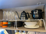RV rental kitchen: organized shelves with clear glasses, Apexstone kettle, Dash rice cooker, mugs, cast iron, and dishes.