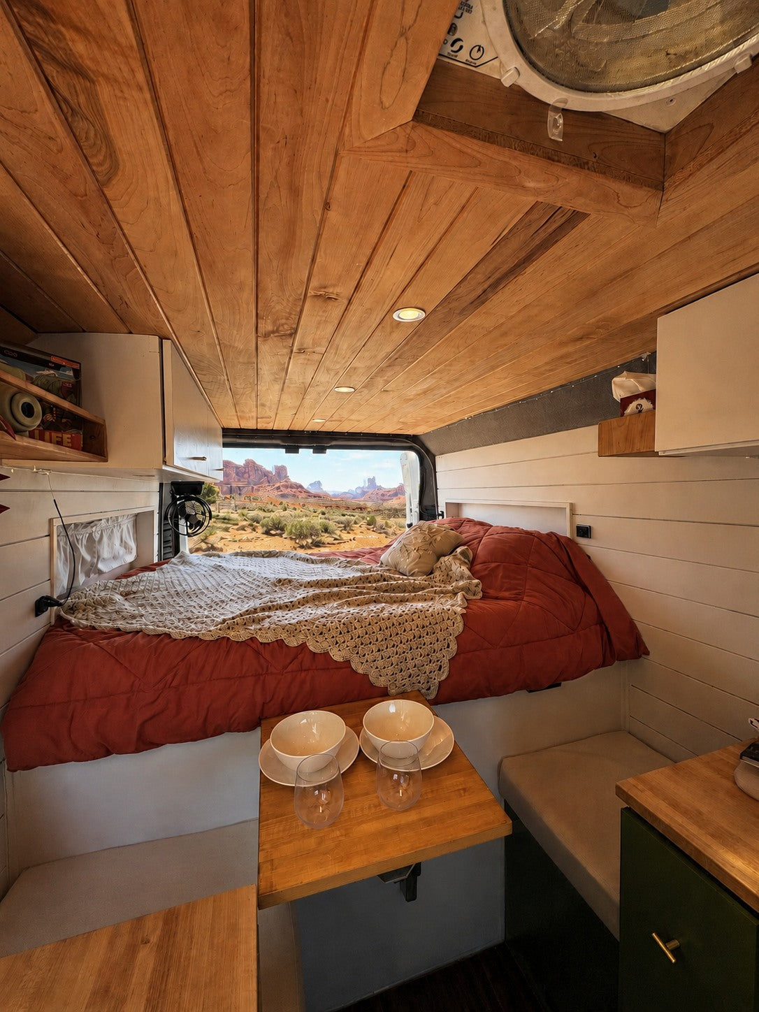 Cozy RV rental interior with a bed, dining area, and stunning desert view. Perfect for adventure travel and van life.