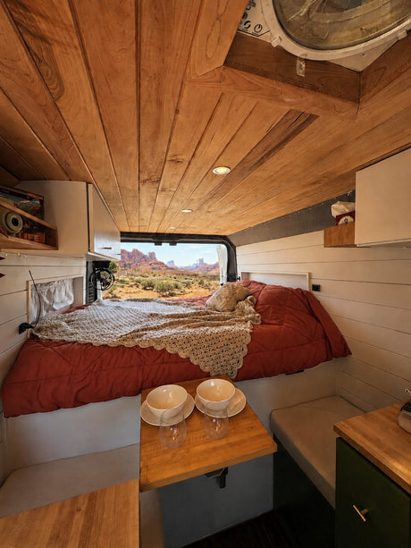 Cozy RV rental interior with a bed, dining area, and stunning desert view. Perfect for adventure travel and van life.