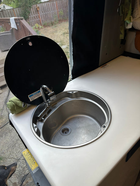 RV rental: Compact sink with faucet, lifted cover, & countertop. Practical for mobile kitchen needs in a camper.