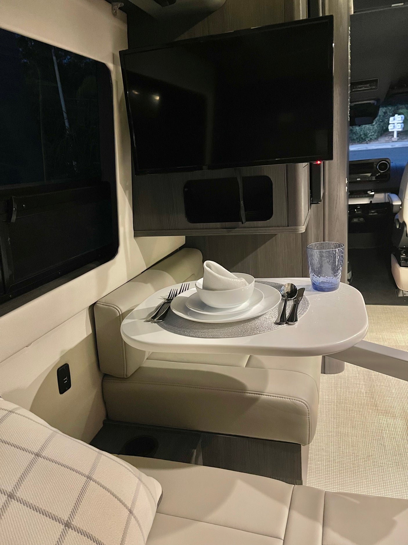 Cozy rv rental interior with a set dining table and TV, perfect for travel comfort. Modern mobile living.