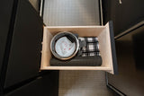 Organized wooden drawer in an RV rental, showing kitchen essentials: pot, measuring cup, towel, and silicone mat.