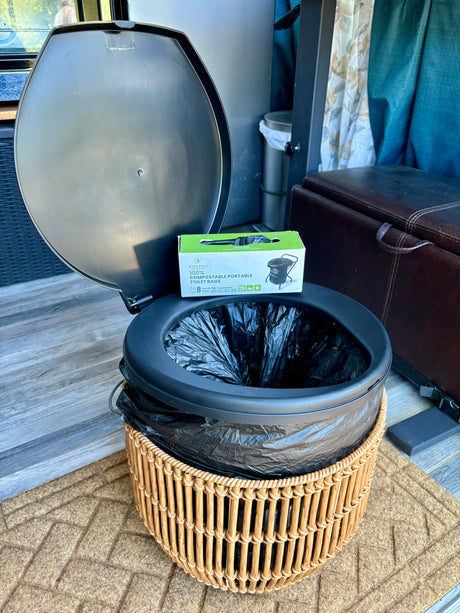 Essential for an RV rental: a portable toilet with SUPERBIO compostable bags, set on a textured floor mat.