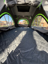RV rental rooftop tent: cozy interior with quilted bed and scenic outdoor views.