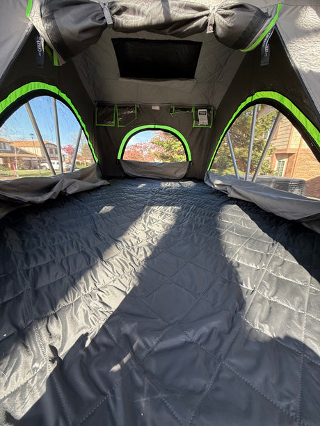 RV rental rooftop tent: cozy interior with quilted bed and scenic outdoor views.
