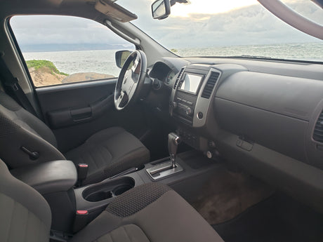 Interior of an RV rental SUV, featuring dashboard, steering wheel, and a vast ocean view.