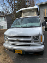 White pop-top camper van, a perfect Alaska RV rental. Front view shows details for your next adventure.