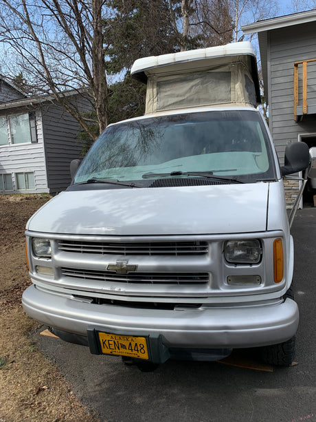 White pop-top camper van, a perfect Alaska RV rental. Front view shows details for your next adventure.