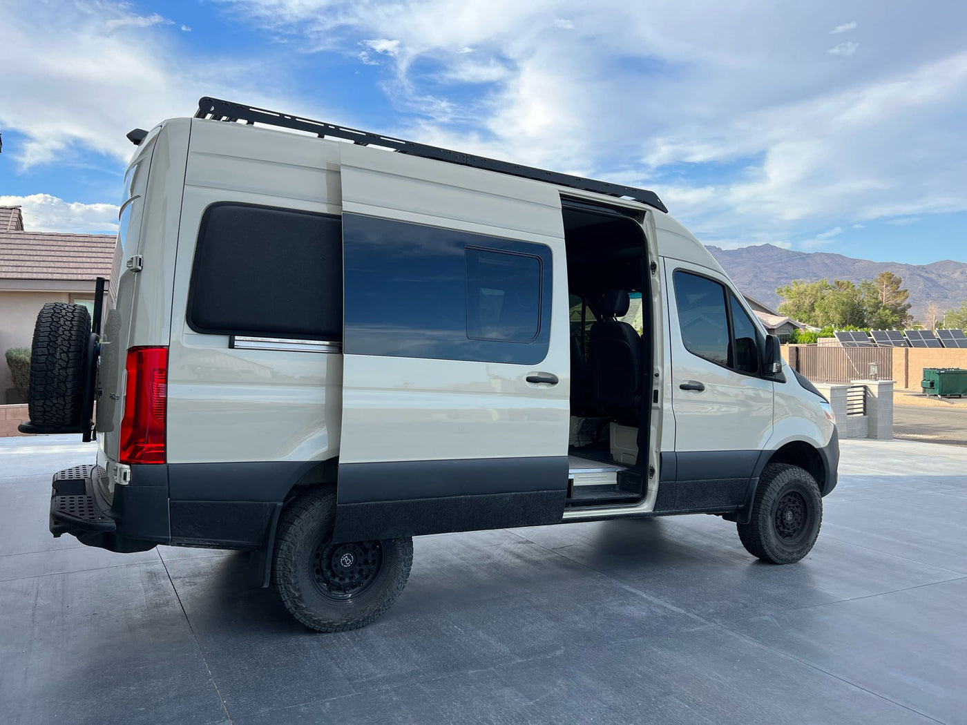  and a dog in a rocky desert landscape.|Spacious custom camper van with open side door revealing a bed inside — photo 5
