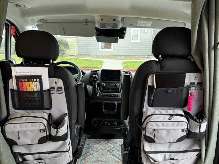 RV rental van interior: organized front seats with multi-pocket storage, ideal for van life and road trip essentials.